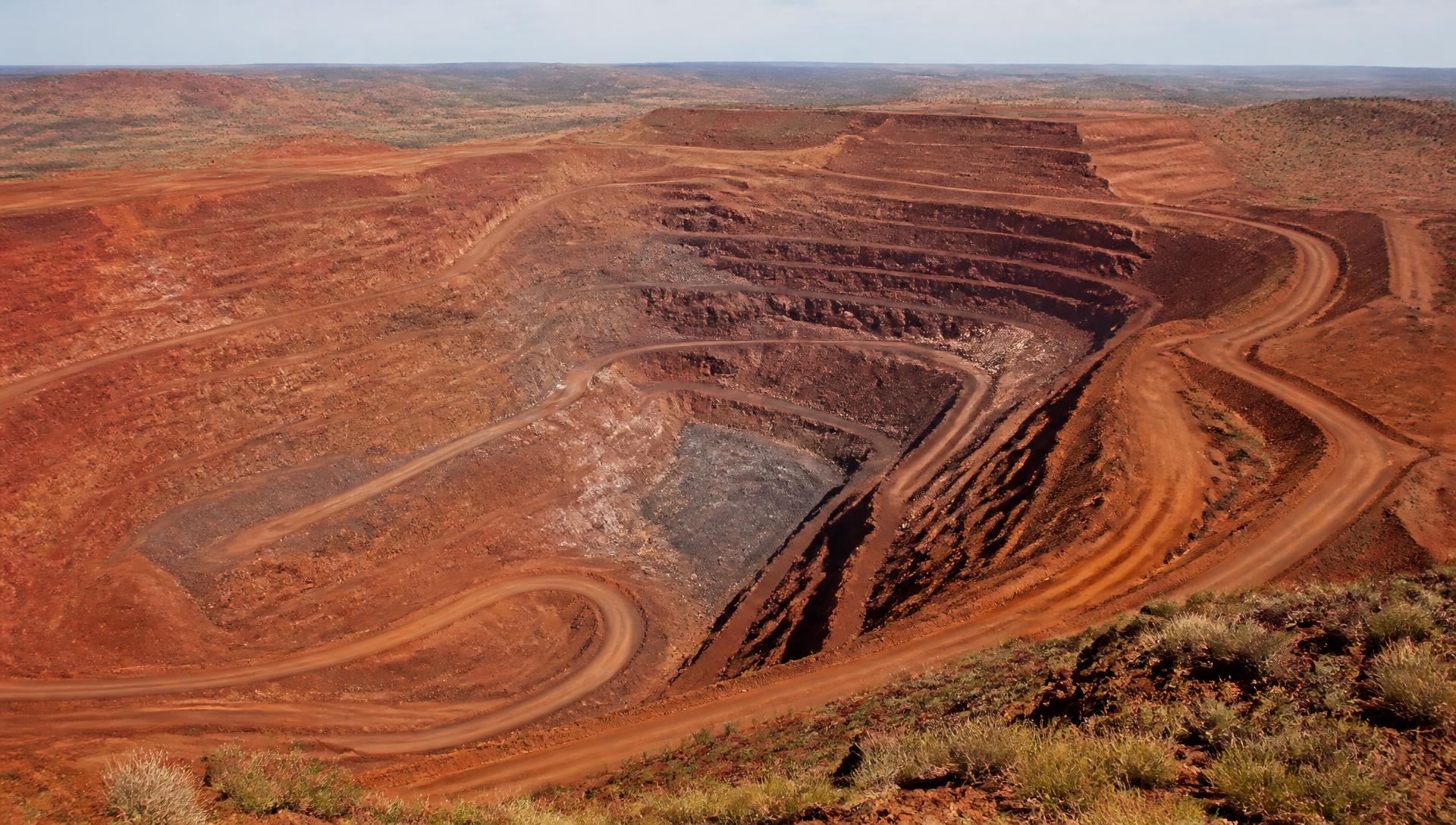 Aerial view of an open-cut mine pit with terraced benches in red Western Australian earth